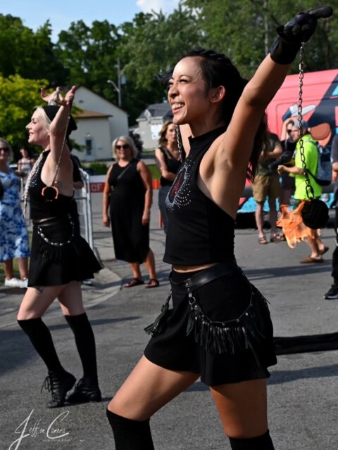 Two female fire poi performers smiling and posing at the end of a performance wearing black skort and matching halter tank tops with rhinestone design.